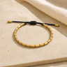 Bracelet Tibétain Perles de Cuivre Doré Tressé à la Main — photographie produit sur travertin beige