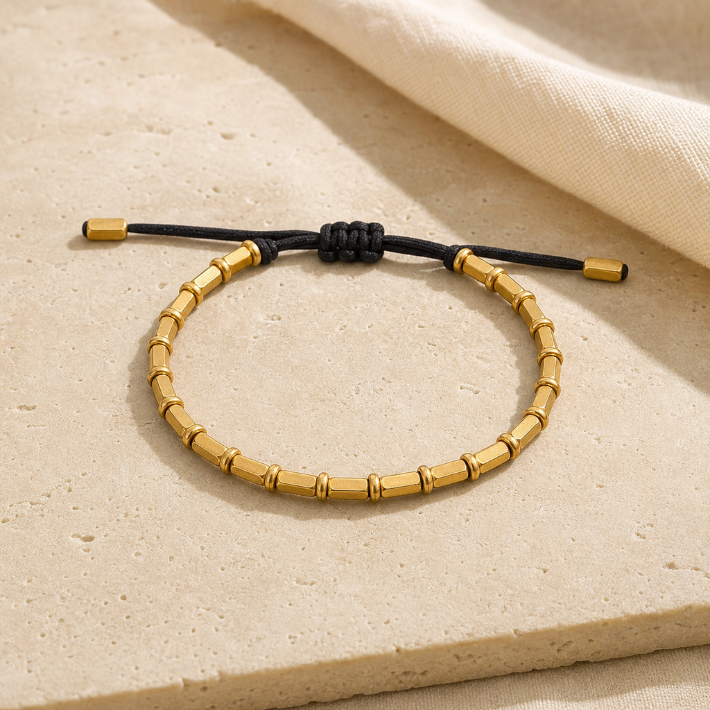 Bracelet Tibétain Perles de Cuivre Doré Tressé à la Main — photographie produit sur travertin beige