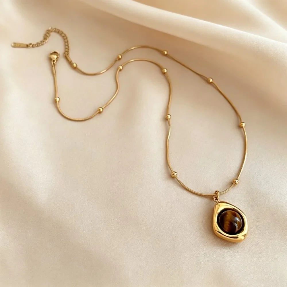 Collier œil de tigre doré porté avec pendentif sur chaîne serpent